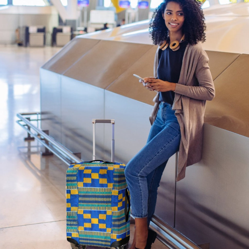The Passport Hustle Luggage Cover Blue Kente Cloth Carry on waiting for checked luggage at baggage claim. 